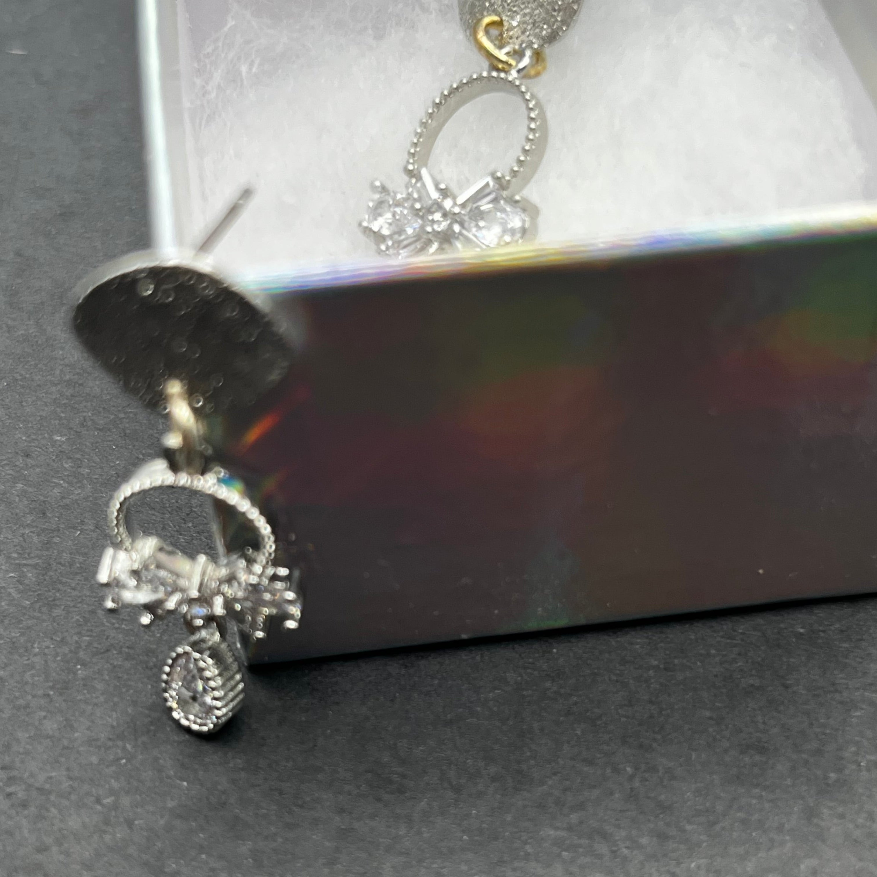 Silver earrings with charms on a dark surface